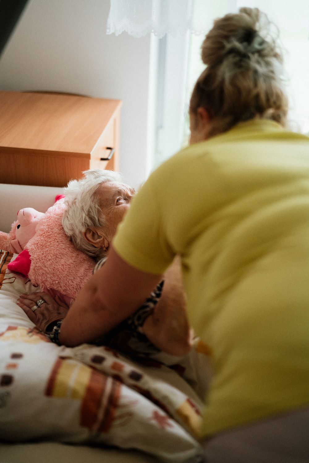 A care professional assisting an older adult in a nursing facility